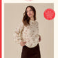 Sirdar knitting pattern cover for 'Embers' double knitting, showing a woman wearing a cream-colored knit sweater with small brown embroidered details. The cover features the Sirdar brand logo, design number 10958, and product color details.
